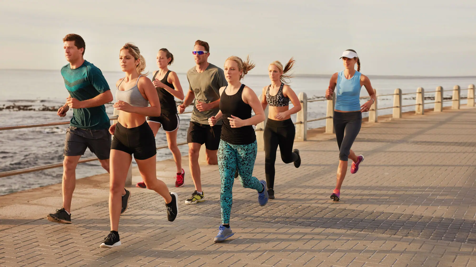 A group of people running together along a beach boardwalk